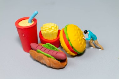 Dev Fast Food 'u iten minyatür figür bu neşeli sahne mizahi bir şekilde diyet, aşırı tüketim ve çaba temaları vurguluyor.