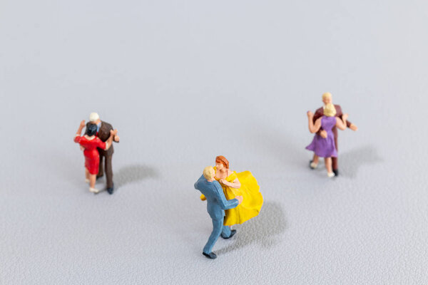 Small figurines of dancing couples in colorful outfits on a light textured surface