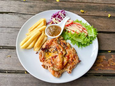 Kızarmış tavuk bifteği ve patates kızartması. Köy ahşabının üzerinde beyaz tabakta taze salata.