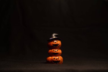 Karanlık arka planda cadı şapkalı balkabakları istiflenmiş, Cadılar Bayramı dekorasyon konsepti.