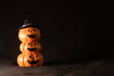 Karanlık arka planda cadı şapkalı balkabakları istiflenmiş, Cadılar Bayramı dekorasyon konsepti.