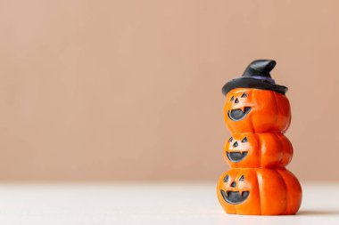 Yığılmış Cadılar Bayramı balkabağı heykelciği oyulmuş yüzler ve tarafsız arkaplanda cadı şapkası.