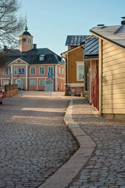 Cobblestone roads in old town Porvoo, Finland. Many colorful wooden houses and buildings like shops, cafes, museums and residential houses. Sunlight peeking through the buildings.