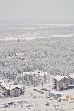 Aerial picture of a rural town and forest during the winter in Lapland, Finland. Many snow-covered houses and trees. Ski resort, hotels and shopping. 