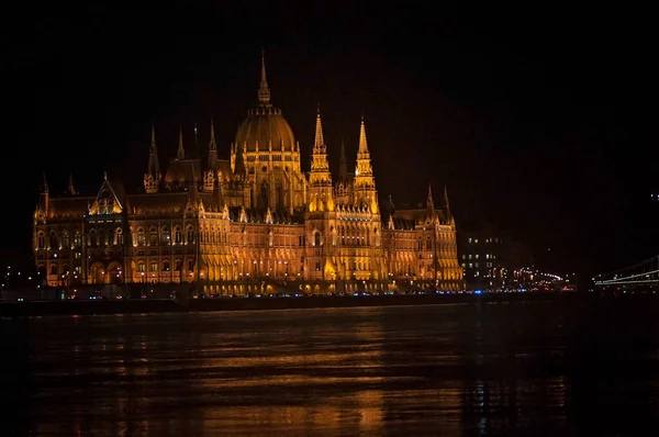 Historic Hungarian parliament building, in Budapest at night. The river Danube and reflection of the building in water. Lit up old building with domes and towers.