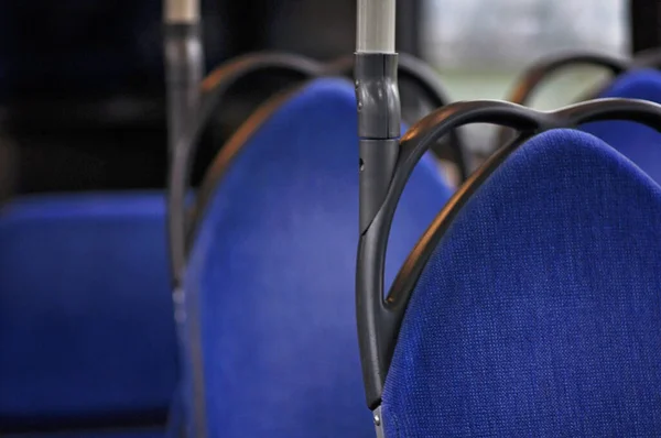 Bright blue seats in a bus with black and metallic details. Black handles on the blue seats in empty bus with no people. Going on a bus trip, Finnish public transport.