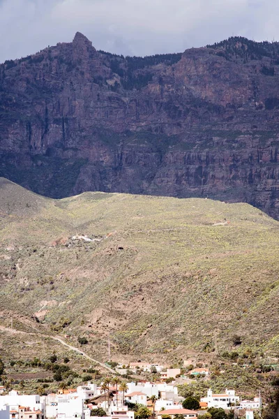 İspanya, Gran Canaria 'daki dağların ya da kayalık tepelerin çarpıcı manzarası. Dağlar arasında bir vadide birçok ev ve bina olan bir kasaba. Yürüyüş ve güzel doğa manzarası..