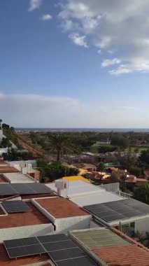 İspanya, Gran Canaria 'da tatil beldesi. Ufukta bir sürü evi, palmiye ağaçları ve okyanusu olan bir otel manzarası. Bulutlu mavi gökyüzü, güneş sıcacık parlıyor. Kanarya Adalarında Seyahat.