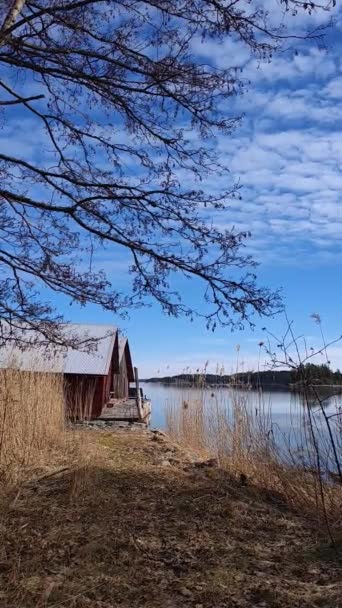 欧洲海边或湖边的木制房屋 别墅的外围建筑 棚屋或桑拿式建筑都在水边 春天里阳光明媚 天空一片蓝天 乌云密布 — 图库视频影像