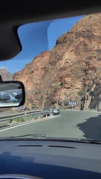 スペインのグラン カナリアの山の中で車で運転 アスファルトの道路を通過する他の車 両側に山 木や他の植生の風景です 青い空と晴れた日 — ストック動画