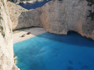 Yunanistan 'ın Zakynthos adasındaki Navagio Sahili' nin (Batık Kumsalı) nefes kesici manzarası. Bu dünyaca ünlü koy dik kireçtaşı kayalıkları, canlı turkuaz suları ve beyaz kumların üzerinde duran paslı bir gemi enkazı barındırıyor. Yukarıdan çekilen resim yüksekliği