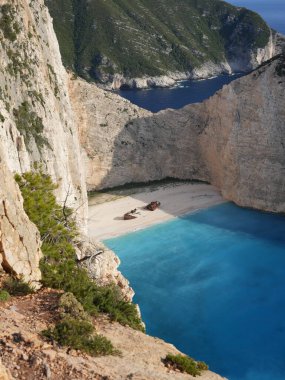 Yunanistan 'ın Zakynthos adasındaki Navagio Sahili' nin (Batık Kumsalı) nefes kesici manzarası. Bu dünyaca ünlü koy dik kireçtaşı kayalıkları, canlı turkuaz suları ve beyaz kumların üzerinde duran paslı bir gemi enkazı barındırıyor. Yukarıdan çekilen resim yüksekliği