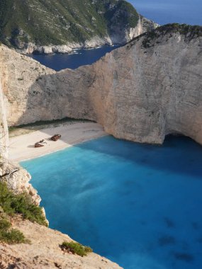 Yunanistan 'ın Zakynthos adasındaki Navagio Sahili' nin (Batık Kumsalı) nefes kesici manzarası. Bu dünyaca ünlü koy dik kireçtaşı kayalıkları, canlı turkuaz suları ve beyaz kumların üzerinde duran paslı bir gemi enkazı barındırıyor. Yukarıdan çekilen resim yüksekliği