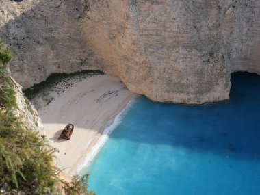 Yunanistan 'ın Zakynthos adasındaki Navagio Sahili' nin (Batık Kumsalı) nefes kesici manzarası. Bu dünyaca ünlü koy dik kireçtaşı kayalıkları, canlı turkuaz suları ve beyaz kumların üzerinde duran paslı bir gemi enkazı barındırıyor. Yukarıdan çekilen resim yüksekliği