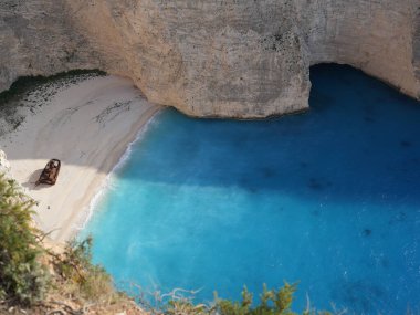 Yunanistan 'ın Zakynthos adasındaki Navagio Sahili' nin (Batık Kumsalı) nefes kesici manzarası. Bu dünyaca ünlü koy dik kireçtaşı kayalıkları, canlı turkuaz suları ve beyaz kumların üzerinde duran paslı bir gemi enkazı barındırıyor. Yukarıdan çekilen resim yüksekliği