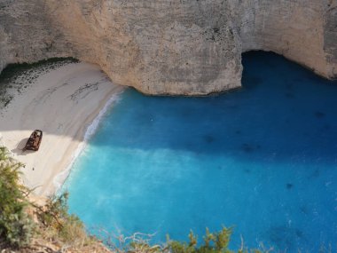 Yunanistan 'ın Zakynthos adasındaki Navagio Sahili' nin (Batık Kumsalı) nefes kesici manzarası. Bu dünyaca ünlü koy dik kireçtaşı kayalıkları, canlı turkuaz suları ve beyaz kumların üzerinde duran paslı bir gemi enkazı barındırıyor. Yukarıdan çekilen resim yüksekliği