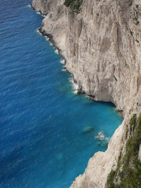 Yunanistan 'ın Zakynthos adasından çarpıcı bir kıyı manzarası, dik uçurumlara ve İyon Denizi boyunca görünen Mora Dağları' na bakan derin mavi denize bakıyor. Görüntü Akdeniz kıyılarının doğal güzelliklerini yakalıyor, engebeli araziyi birleştiriyor.