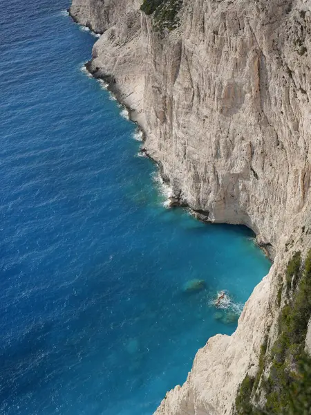 Yunanistan 'ın Zakynthos adasından çarpıcı bir kıyı manzarası, dik uçurumlara ve İyon Denizi boyunca görünen Mora Dağları' na bakan derin mavi denize bakıyor. Görüntü Akdeniz kıyılarının doğal güzelliklerini yakalıyor, engebeli araziyi birleştiriyor.