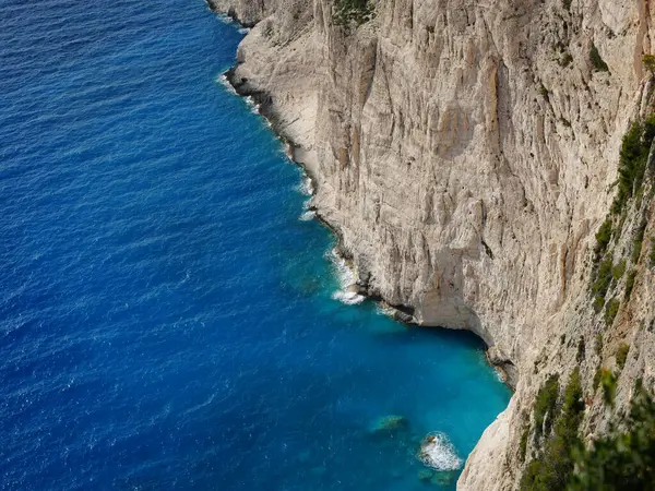 Yunanistan 'ın Zakynthos adasından çarpıcı bir kıyı manzarası, dik uçurumlara ve İyon Denizi boyunca görünen Mora Dağları' na bakan derin mavi denize bakıyor. Görüntü Akdeniz kıyılarının doğal güzelliklerini yakalıyor, engebeli araziyi birleştiriyor.