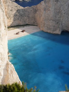 Yunanistan 'ın Zakynthos adasındaki Navagio Sahili' nin (Batık Kumsalı) nefes kesici manzarası. Bu dünyaca ünlü koy dik kireçtaşı kayalıkları, canlı turkuaz suları ve beyaz kumların üzerinde duran paslı bir gemi enkazı barındırıyor. Yukarıdan çekilen resim yüksekliği