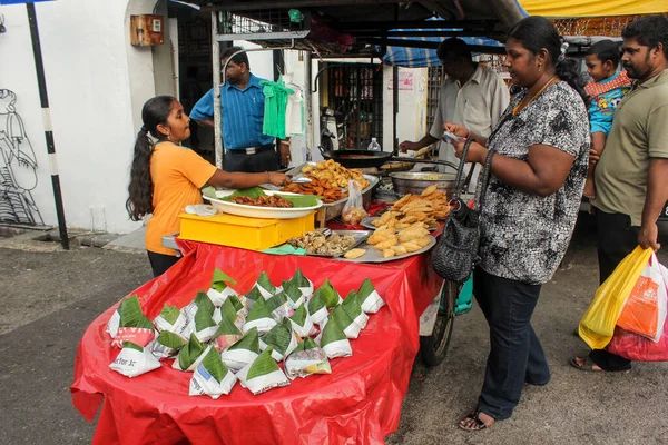 stock image Georgetown, Penang, Malaysia - November 2012: A girl selling deep fried Indian snacks at a roadside hawker stall in Little India in George Town, Penang.