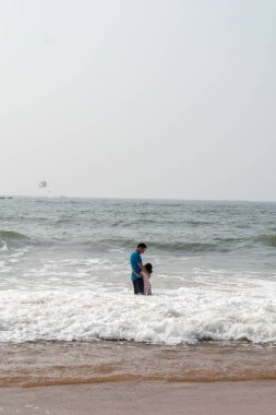 Candolim, Goa, Hindistan - Ocak 2023: Hintli bir baba Sinquerim 'de bir plajda kızıyla oynuyordu.