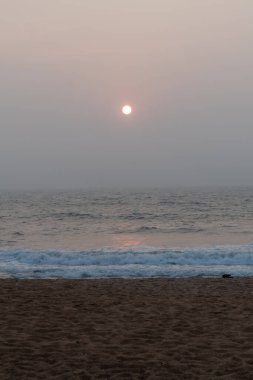 Goa 'da Candolim' de bir plajda, denizin üstünde gün batımının huzurlu manzarası.