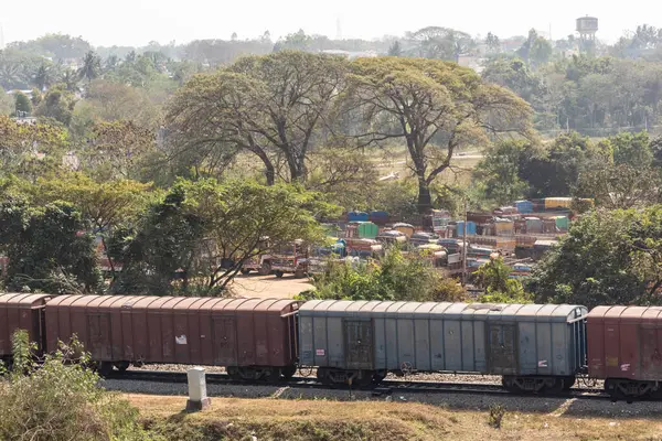 Hassan, Karnataka, Hindistan - 9 Ocak 2023: Bir kasabanın yeşil mahallesinden geçen trenin hava görüntüsü.