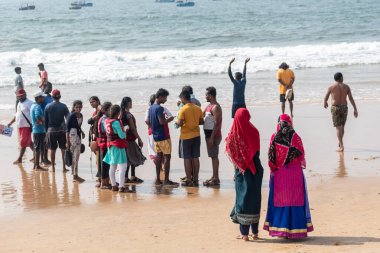 Calangute, Goa, Hindistan - Ocak 2023: Kuzey Goa 'da kalabalık bir plajda yürüyen renkli elbiseli iki kadın.