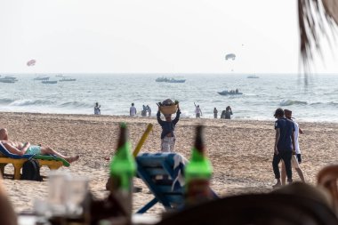 Calangute, Goa, Hindistan - Ocak 2023: Goa 'da bir plajda kafasında meyve sepeti taşıyan Hintli bir kadın satıcı.