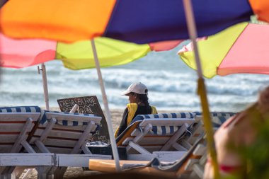 Calangute, Goa, Hindistan - Ocak 2023: Goa 'da bir sahil barakasında, güverte sandalyesinde tek başına oturan kep takan Hintli bir kadın.