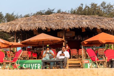Calangute, Goa, Hindistan - Ocak 2023: Calangute 'daki popüler plaj kulübesinde oturan iki Hintli turist.