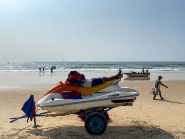 Calangute, Goa, Hindistan - Ocak 2023: Calangute 'daki popüler turist plajında jet ski üzerinde yatan bir adam.
