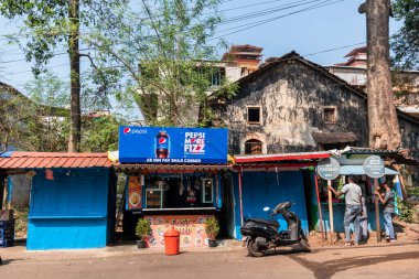 Margao, Goa, Hindistan - Ocak 2023: Madgaon 'da eski bir yıpranmış evin altında Pepsi gibi yiyecek ve soğuk içecek satan bir fast food tezgahı.