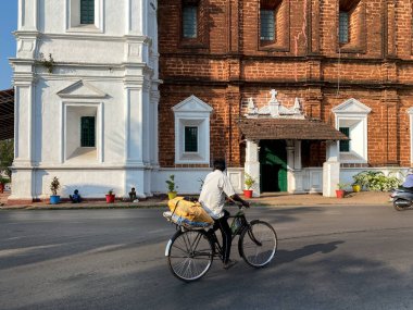 Margao, Hindistan - 21 Ocak 2023: İnsanlar Goa 'daki Kutsal Ruh Antik Kilisesi' nin önünden bisikletle geçiyorlar.
