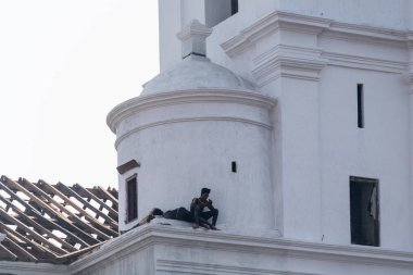 Eski Goa, Hindistan - Ocak 2023: Eski Goa 'daki antik Se Katedrali' nin çatısında oturan iki adam.