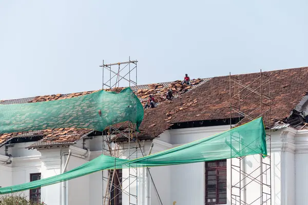 Eski Goa, Hindistan - Ocak 2023: Assisi Kilisesi 'nin St. Francis restorasyonu sırasında çatıdaki fayansları tamir eden işçiler.