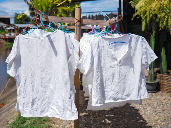 太陽の下で竹の服の行にハンガーでぶら下がって乾燥した白いシャツ — ストック写真