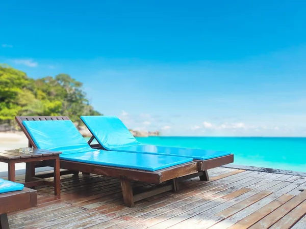 Wooden blue sun bed on wood floor over beach against blue sky. Happy summer holidays vacation background.