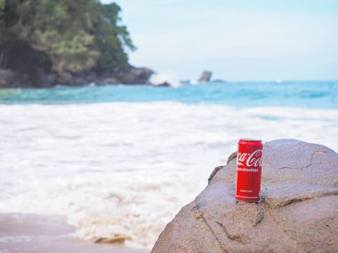 Phang Nga, Tayland - 14 Şubat 2019: Coca-Cola yaz sahili arka planında kayanın üzerinde meşrubat içebilir.