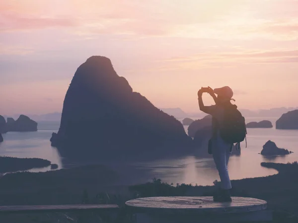 stock image Silhouette woman tourist taking photograph by mobile phone at sunrise Samet Nangshe View Point, Phang Nga, Thailand. 