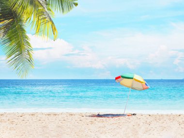 Yaz plaj arka plan. Mavi gökyüzü ve deniz manzarası üzerinde kum üzerinde renkli şemsiye ve paspas.