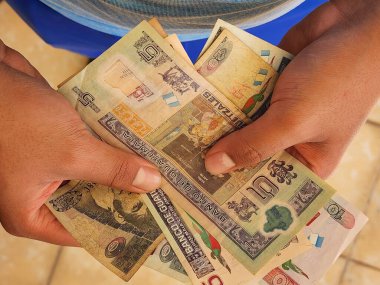 Guatemala banknotlarını farklı değerlerde tutan ve sayan bir adamın elleri