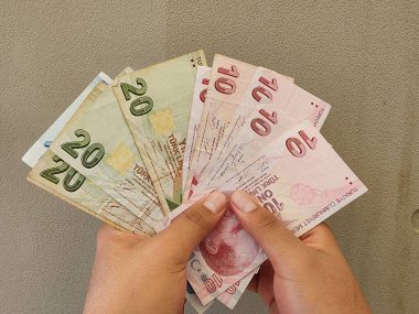 Elinde farklı mezheplerden Türk banknotları tutan bir adamın elleri