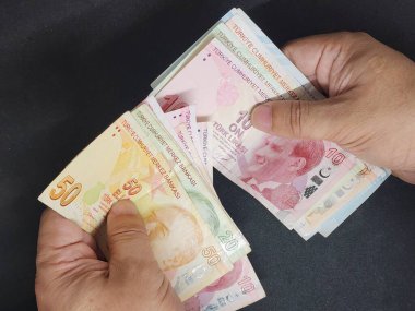 Türk banknotlarını farklı değerlerde tutan ve sayan bir adamın elleri