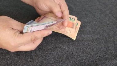 approach to hands of a man holding and counting brazilian banknotes