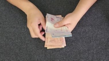 hands of a woman holding and counting brazilian banknotes of different denomination