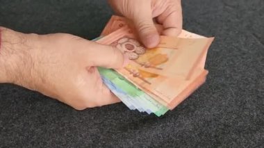 hands of a man holding and counting malaysian banknotes