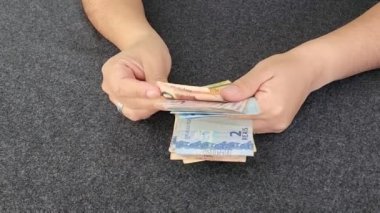 Brezilya banknotlarını tutan ve sayan bir kadının elleri