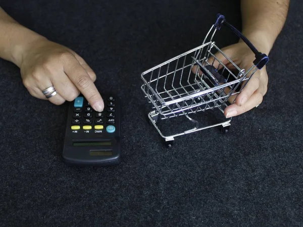 Mãos Uma Mulher Segurando Carrinho Compras Tocando Uma Calculadora Mesa — Fotografia de Stock